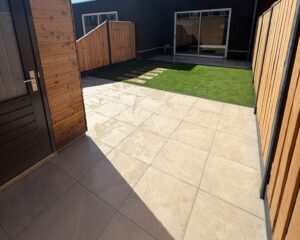 Tuin met sierbestrating, kunstgras en schutting bij woning