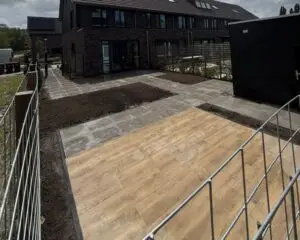 Tuinaanleg met bestrating, houten vlonder en hekwerk bij woning